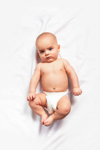 Caucasian funny child in white nappy lies on light background. top view. children's hygiene