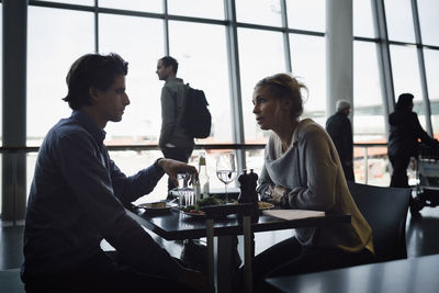 Businesspeople talking while having food at cafe in airport