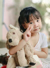 Close-up portrait of cute girl gesturing while holding stuffed toy
