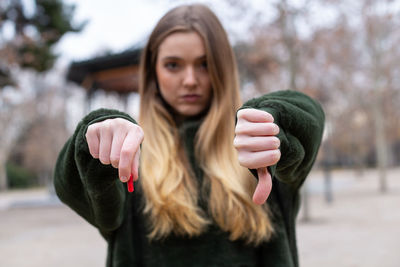 Close-up portrait of woman with pill showing thumbs down 