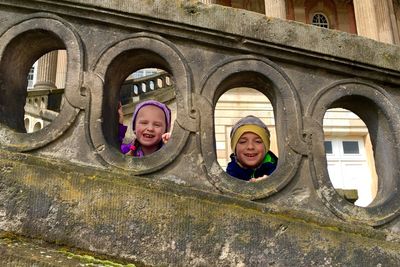 Portrait of smiling siblings seen through railing