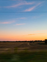 Scenic view of field against sky at sunset