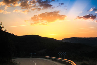 Scenic view of road by mountains against sky during sunset