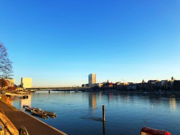 City by river against clear blue sky