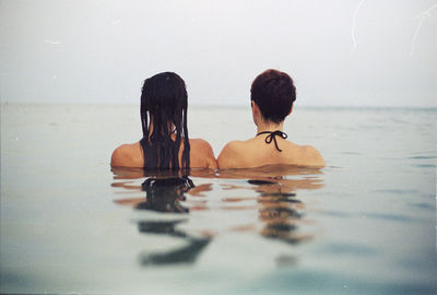 Rear view of friends swimming in lake