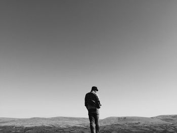Man standing on landscape against clear sky