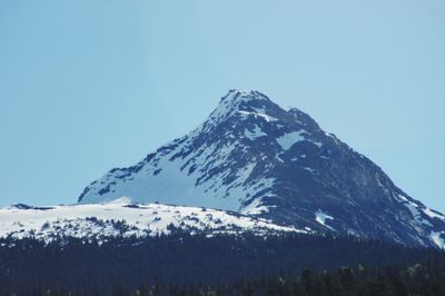 Low angle view of snowcapped mountains against clear blue sky