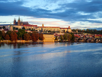 Bridge over river by buildings in city against sky