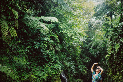 Full length of woman amidst trees in forest