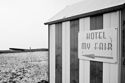 Information sign on beach hut against clear sky