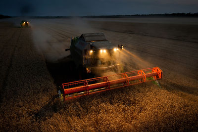 High angle view of illuminated combine harvester on farm