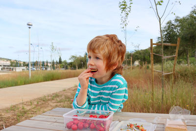 The blond boy takes a bite of a cookie and looks off into the distance. a serious five-year-old boy