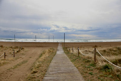 Walkway amidst field against sky