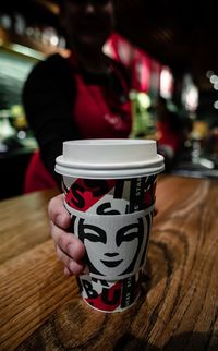 Close-up of hand holding coffee cup on table