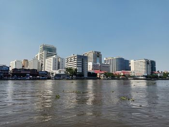 River by city buildings against clear sky