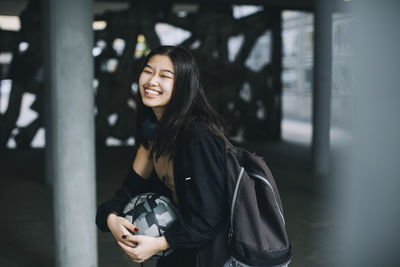 Cheerful female teenager laughing in parking garage