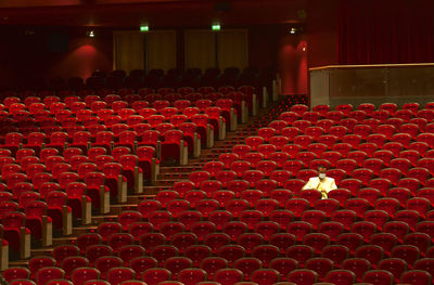 Man wearing mask sitting on chairs in theater