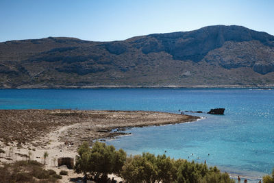 Scenic view of sea and mountains against clear blue sky