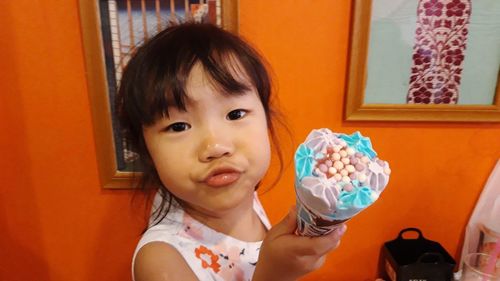 Portrait of cute girl holding ice cream at home