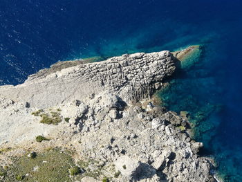 Rock formation on sea shore against blue sky