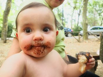 Close-up of baby eating food while sitting with father at park