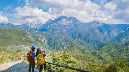 Rear view of people walking on mountain against sky