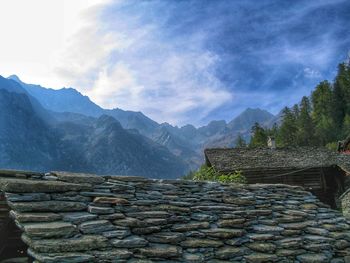 Stack of logs on mountain against sky