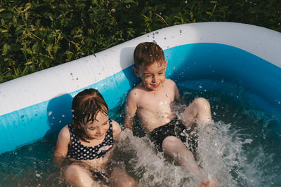Cheerful happy children lie in the pool and splash with their feet. friends spend summer leisure 