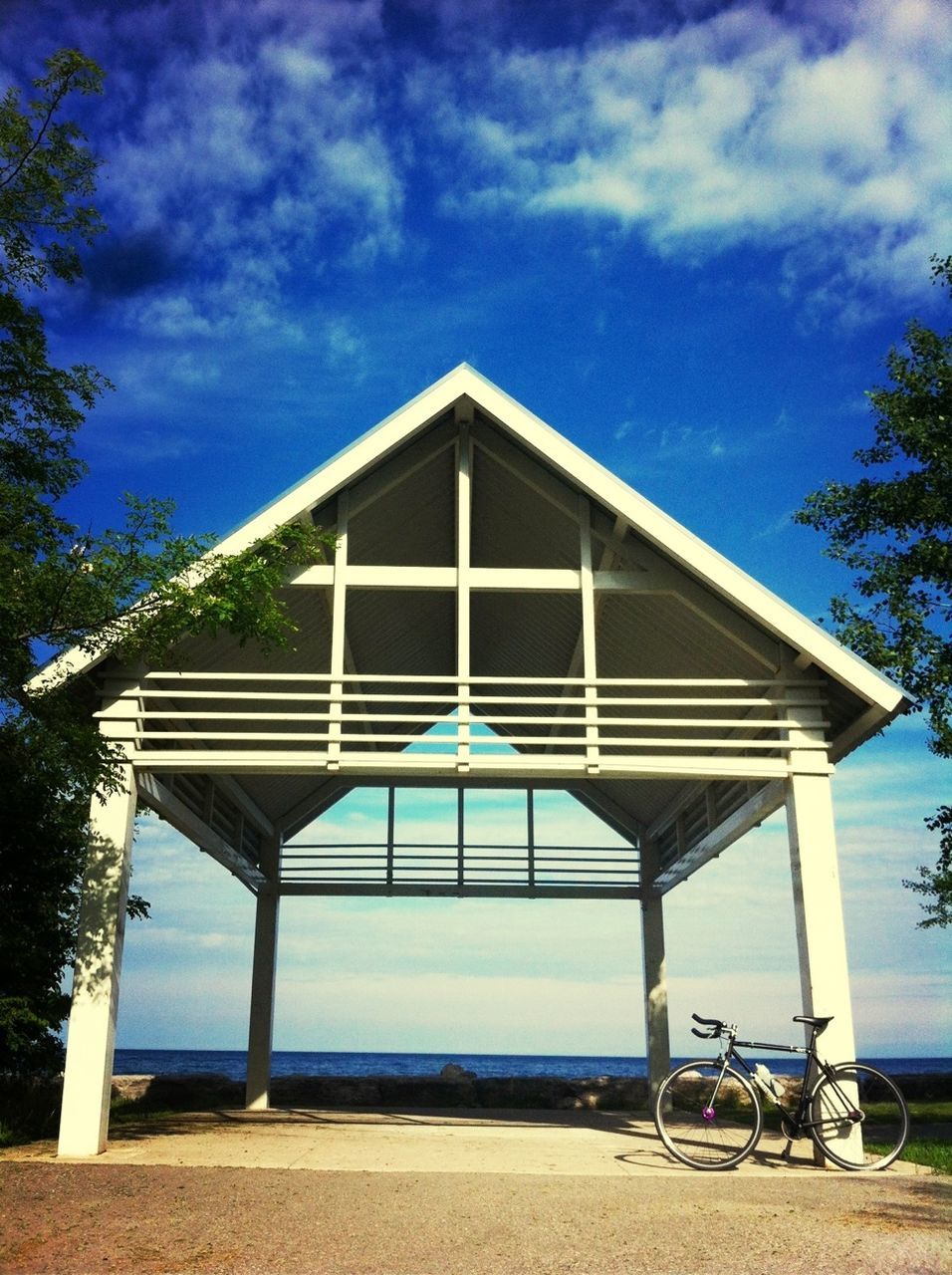 sky, built structure, beach, sea, cloud - sky, architecture, railing, cloud, horizon over water, tree, water, sunlight, blue, sand, day, nature, tranquility, outdoors, shore, shadow