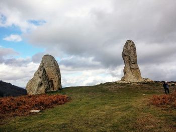 Cross on rock against sky