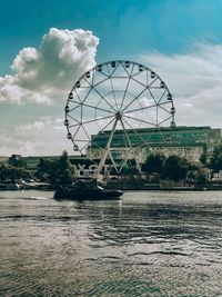 Ferris wheel by river against sky