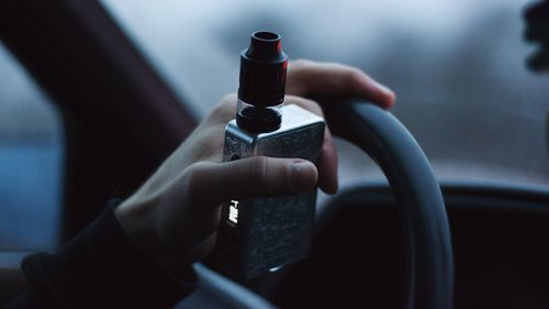 Cropped hand holding equipment while driving car