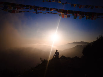 Silhouette man on mountain against sky during sunset