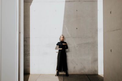 Portrait of woman standing against wall