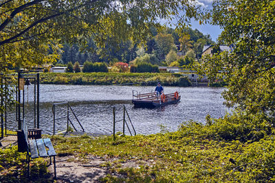 People on boat by river against trees