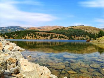 Scenic view of lake by mountain against sky