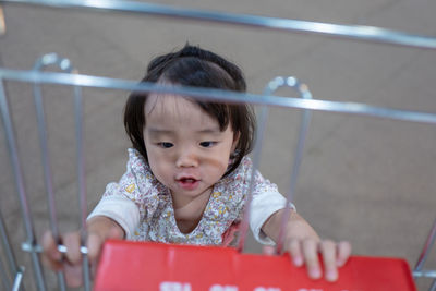 Cute baby girl touching shopping cart