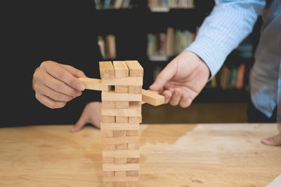 Cropped hands playing with wooden blocks on table