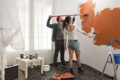 Full length of woman with arms raised standing at home