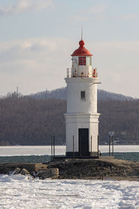 Lighthouse by sea against sky