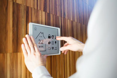 Midsection of man using digital tablet on wall