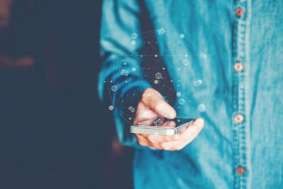 Man using mobile phone while standing against blue background