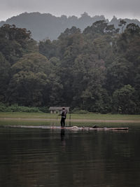 Man standing by lake against mountain
