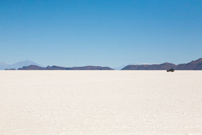 Scenic view of beach against clear blue sky