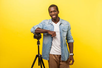 Portrait of smiling young man against yellow background