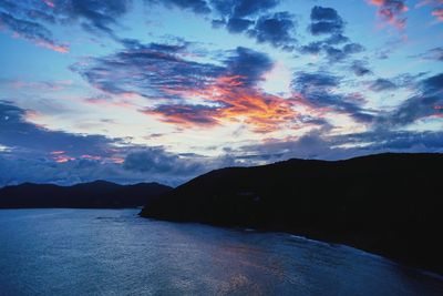 Scenic view of silhouette mountains by sea against sky