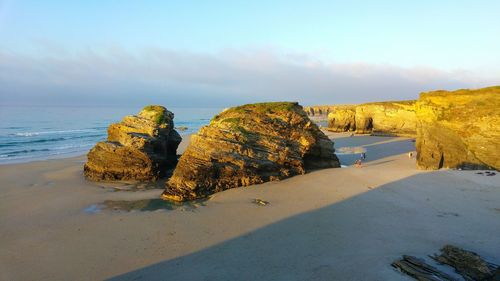 Rock formations at catedrais beach against sky