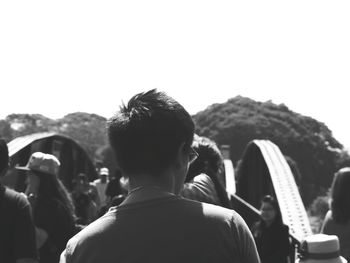 Rear view of people on footbridge against clear sky