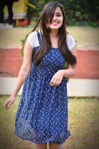 Portrait of smiling young woman standing on field