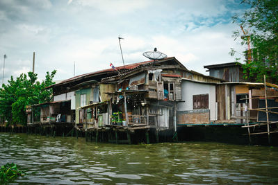 Buildings by river against sky